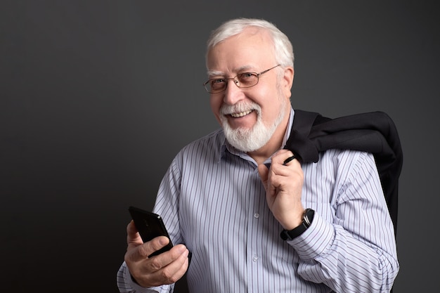 Business-haired, genarbter Mann in Gläsern mit einem Telefon lächelt freundlich