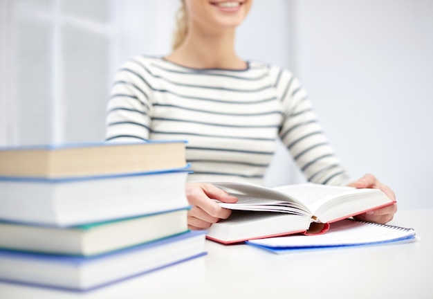 Foto business, high school, bildung, menschen und lernkonzept - nahaufnahme einer jungen frau, die in der schule ein buch liest