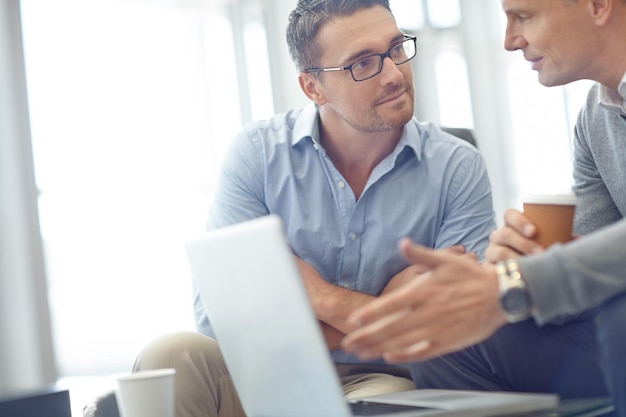 Business-Laptop und Team in Diskussion über Deal-Vorschlag oder Unternehmensidee im Büro Geschäftsleute sprechen über Strategie oder planen Marktstrategie oder Werbung im Gespräch am Arbeitsplatz