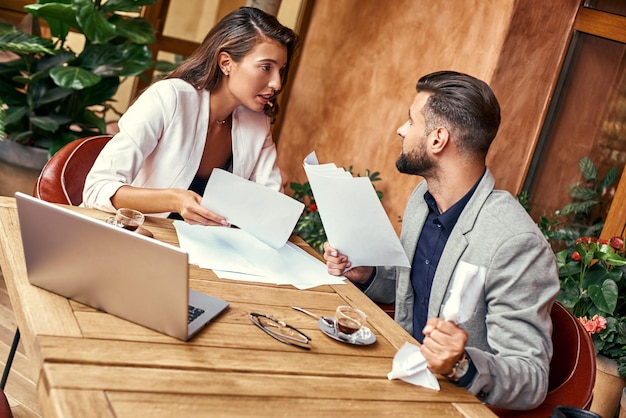 Business-Lunch-Leute sitzen am Tisch im Restaurant und diskutieren über das Projekt lebhafter Mann, der Papier drückt