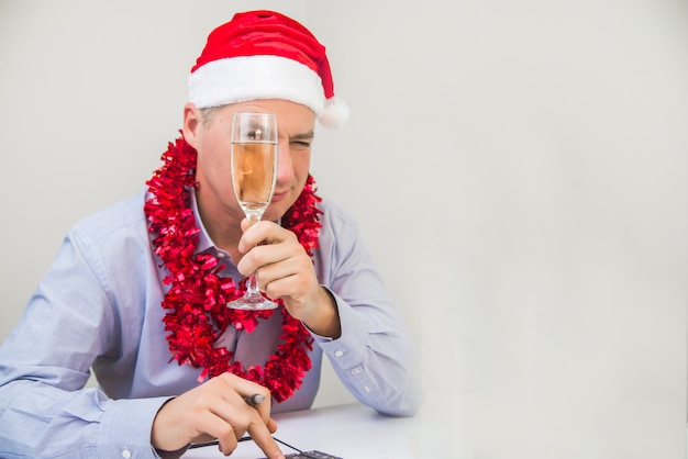 Business-Mann feiern Frohe Weihnachten und Happy New Year tragen Santa Hut. Handsome Geschäftsmann feiert Weihnachten im Büro