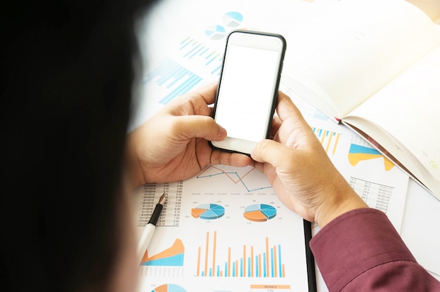 Business-Mann mit Smartphone leere weiße screen.working im Büro mit Dokumenten auf seinem Schreibtisch.