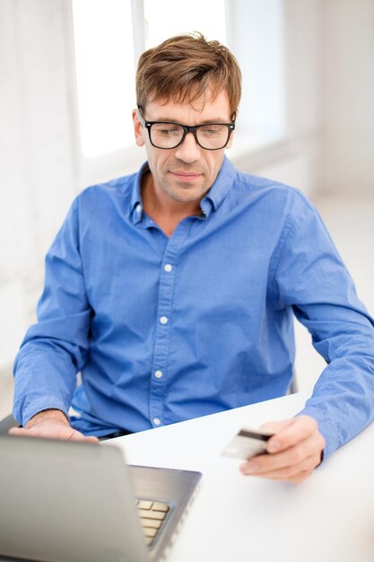 Business, Online-Banking, Internet-Shopping-Konzept - lächelnder Mann mit Laptop und Kreditkarte zu Hause