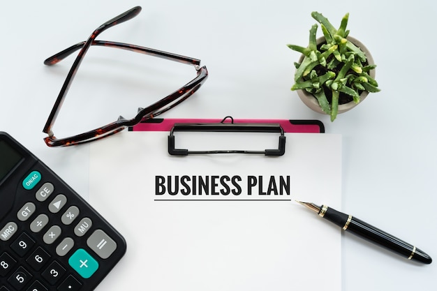 Business-Plan-Konzept, Zwischenablage mit Word-Business-Plan, Stift, Brille und Taschenrechner