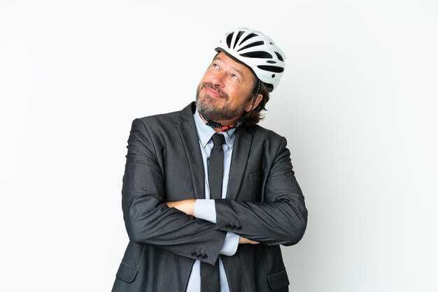 Business senior Mann mit einem Fahrradhelm auf weißem Hintergrund isoliert aufblickt, während er lächelt