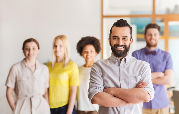 Business, Startup, People und Teamwork-Konzept - glücklicher junger Mann mit Bart über Kreativteam im Büro