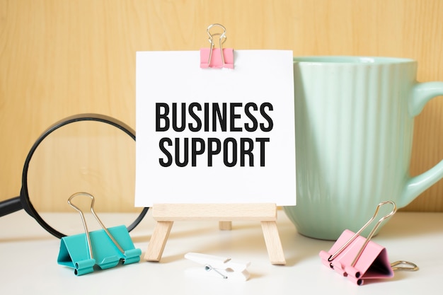 Business-Support-Text auf schwarzem Notizbuch mit Lupe und einem Stift geschrieben. Geschäfts- und Leistungskonzept.