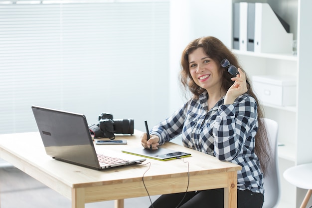 Business-, Webdesign- und Personenkonzept - Frau verwendet Grafiktablett bei der Arbeit am Laptop und beim Lächeln