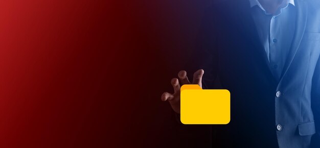 Businessman sostiene el icono de la carpeta El sistema de gestión de documentos o la configuración de DMS por parte de un consultor de TI con una computadora moderna están buscando información de gestión y procesamiento de archivos corporativos
