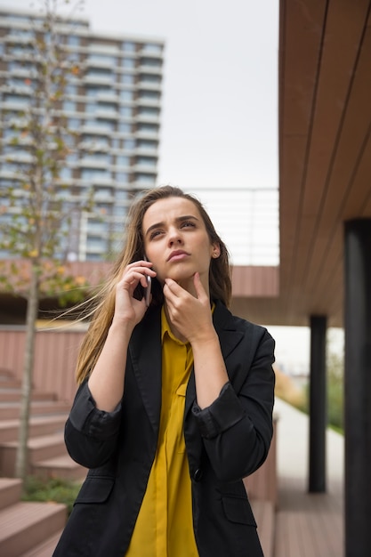 Businesswman preocupado joven que usa el teléfono móvil al aire libre