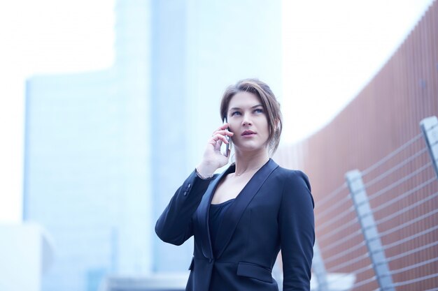 Businesswoma, das mit Mobile in der städtischen Umwelt spricht