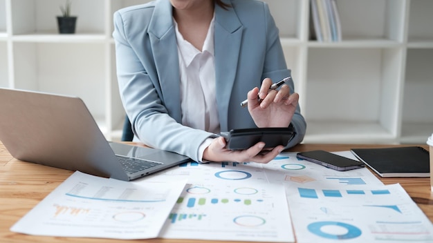 Businesswoman Hand mit Rechner und Laptop berechnet über Finanzbuchhaltung im Bürozimmer