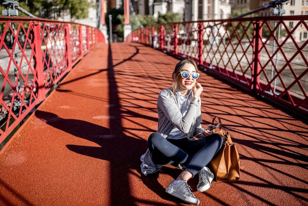 Busineswoman elegante joven sentado con teléfono y bolsa en la pasarela roja en Lyon, Francia.