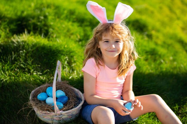 Búsqueda de huevos de Pascua Conejito de Pascua niño con cara linda Niños cazando huevos de Pascua Niño lindo con canasta de Pascua en la hierba