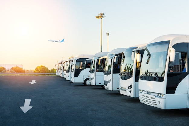 Busse auf dem Parkplatz des Flughafens bei Sonnenaufgang. Urlaub, Reisen, Tourismus und Urlaubskonzept.