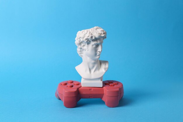 Busto de David antigo com gamepad em fundo azul Jogo Pop conceitual Minimal still life