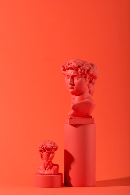 Foto busto de gesso em fundo coral com formas geométricas