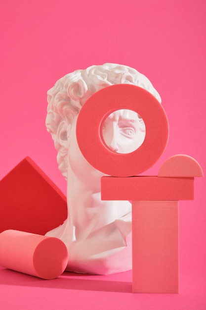 Busto escultórico decorativo blanco y varios posavasos geométricos rosas sobre un fondo rosa