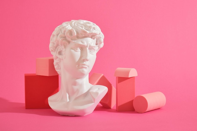 Busto escultórico decorativo blanco y varios posavasos geométricos rosas sobre un fondo rosa