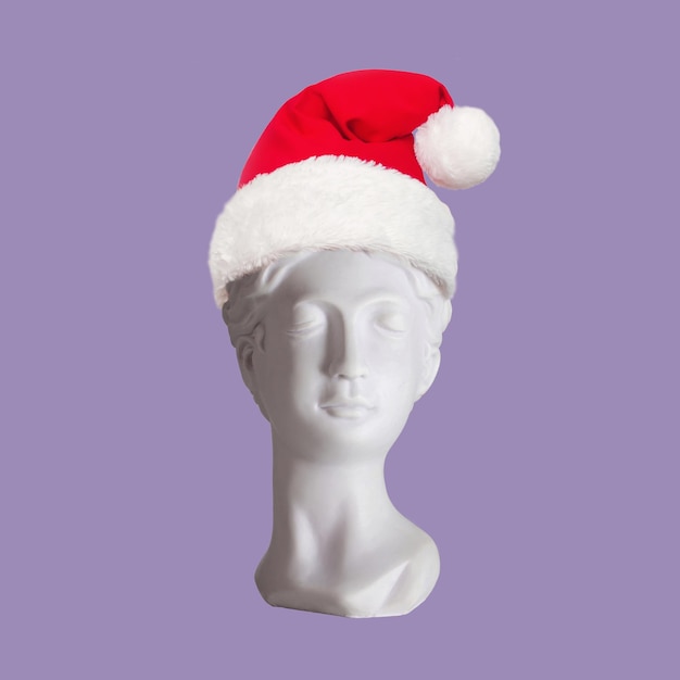 Busto de estatua antigua femenina con sombrero de Papá Noel en la cabeza aislado en un fondo de color púrpura