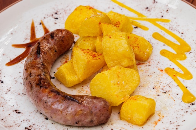 Butifarras de salchichas de cerdo españolas con patatas fritas y salsas en un plato blanco