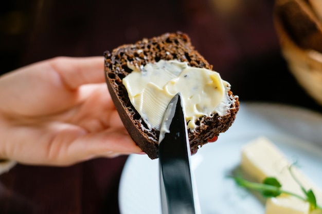 Butter mit einem Messer auf Schwarzbrot streichen