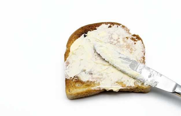 Foto butter mit einem messer auf toast verteilen, isoliert auf weißem hintergrund