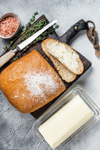 Butterblock und geschnittene Toasts Brot auf einem Holzbrett mit Kräutern