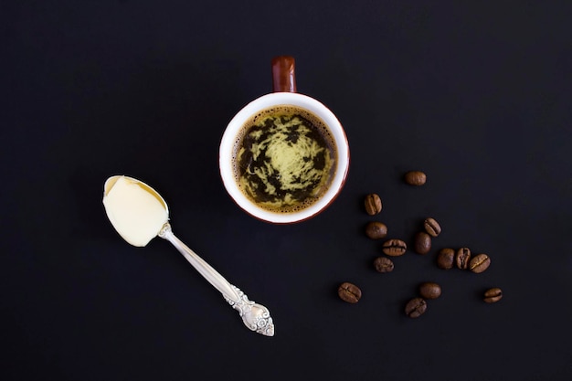 Butterkaffee in der braunen Tasse auf schwarzem Hintergrund Draufsicht Kopierbereich