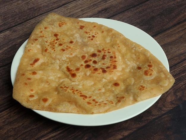 Butterparatha lokalisiert über einem selektiven Fokus des rustikalen hölzernen Hintergrundes