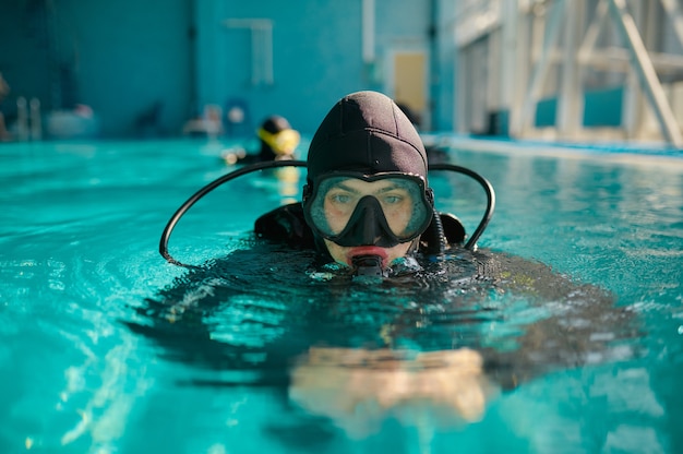 Buzo masculino en equipo de buceo y poses de máscara en la piscina