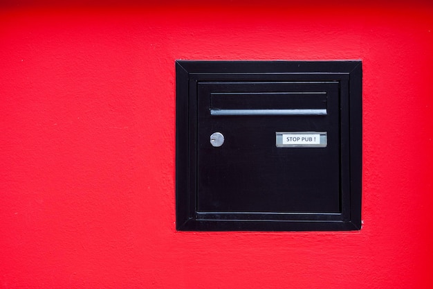 Buzón negro incrustado en una pared roja