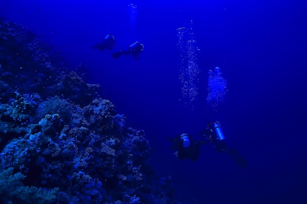 buzos bajo el agua en profundidad en el fondo azul del mar