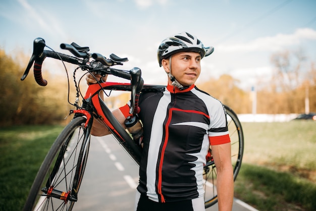 Bycyclist hält das Fahrrad nach dem Radfahren auf der Schulter