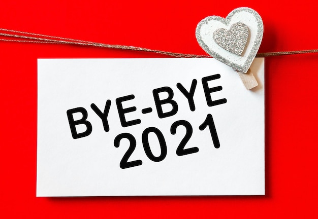 Bye-bye 2021. fundo com corações e cartão. decorações em fundo vermelho. conceito de ano novo