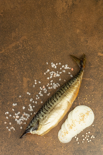 Caballa ahumada en frío sobre fondo de piedra. Rodajas de cebolla, sal marina y mostaza de Dijon