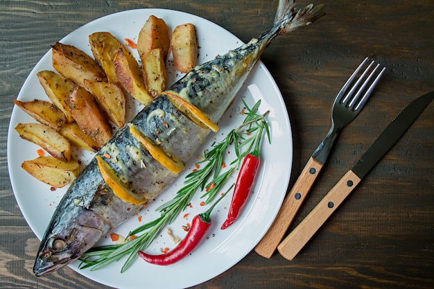 Foto caballa frita servida en un plato, decorada con especias, hierbas y verduras. nutrición apropiada.