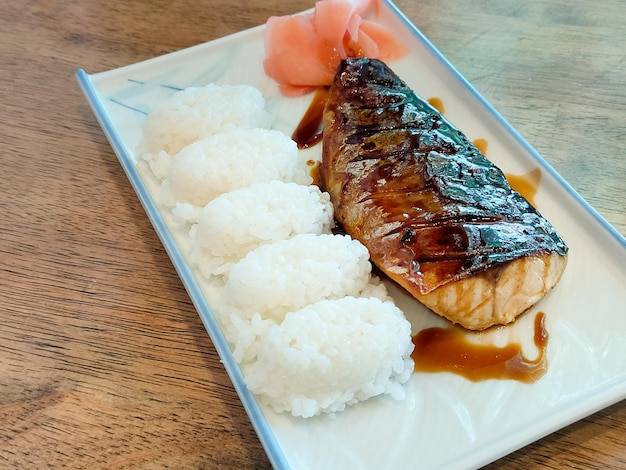 Caballa a la parrilla o pescado saba con salsa japonesa dulce servido con arroz japonés de tamaño bocado en un plato