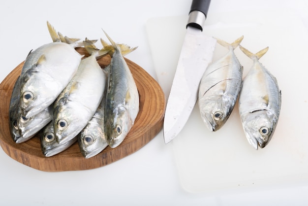 Caballa pescado fresco y cuchillo sobre una tabla de cortar de madera en blanco