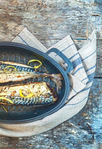 Caballa de pescado con un molde de metal para hornear sobre una toalla y una mesa de madera