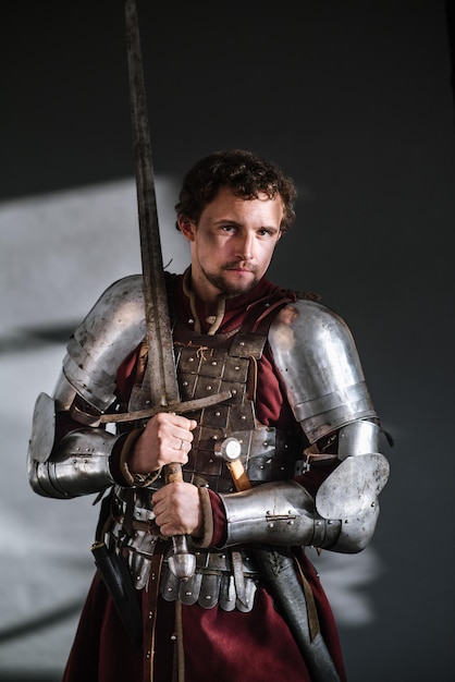 Caballero medieval con armadura y arma sobre fondo oscuro. Retrato del caballero