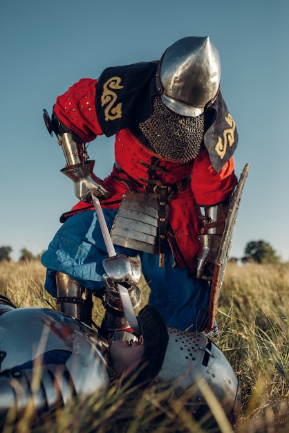 Caballero medieval con armadura y cascos puso su espada en la garganta de su oponente, gran torneo. Antiguo guerrero blindado con armadura posando en el campo