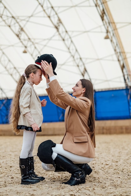 Caballo estilo de vida niño con casco Mujer equipando a niña con casco