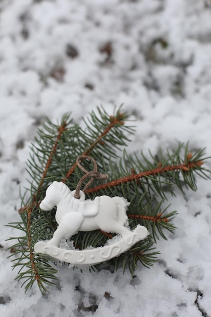 Caballo de juguete de Navidad colgando de ramas verdes en la nieve en invierno Árbol de Navidad Caballo de juguete Regalo Decoración de Año Nuevo