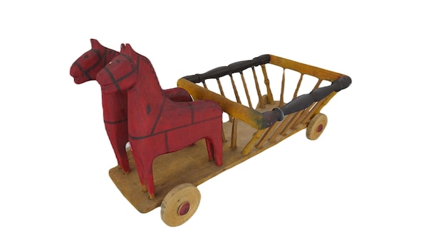 Un caballo de madera y un carro con una silla roja.