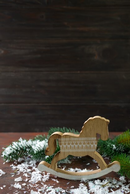 Caballo mecedora de madera de juguete a partir de las decoraciones de Año Nuevo con nieve y árbol de fer.