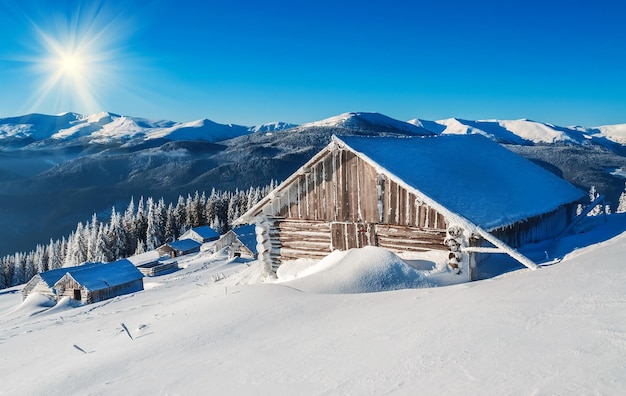 Cabana cabana sob o céu azul em montanhas nevadas de inverno