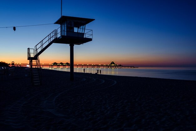 Foto cabana de salva-vidas na praia contra o céu claro ao pôr-do-sol