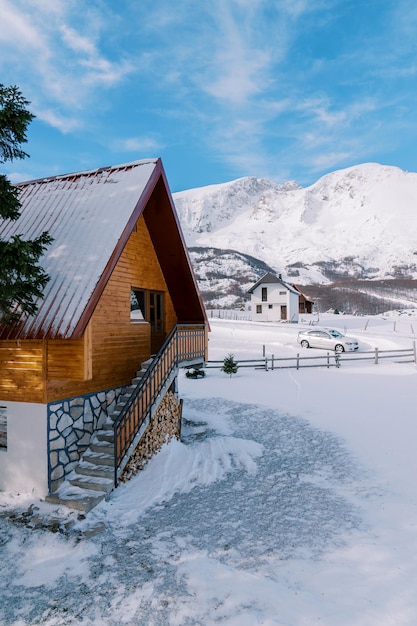 Cabaña de madera de dos pisos cubierta de nieve en un pequeño pueblo en un valle de montaña