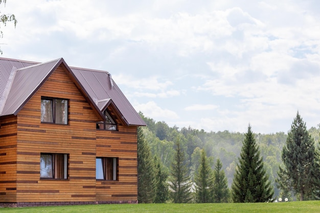 Cabaña de madera de dos plantas con ventanas naturaleza con césped verde. Venta o compra de casas nuevas.